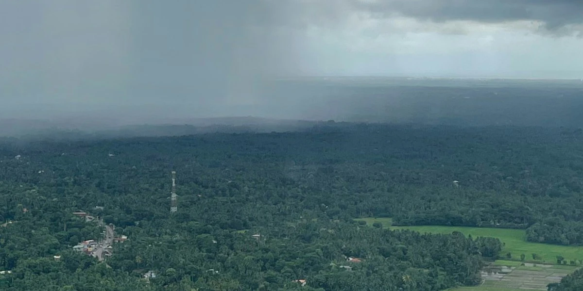 Southwest monsoon rain approaching over green lowland landscape and rice paddies in Sri Lanka